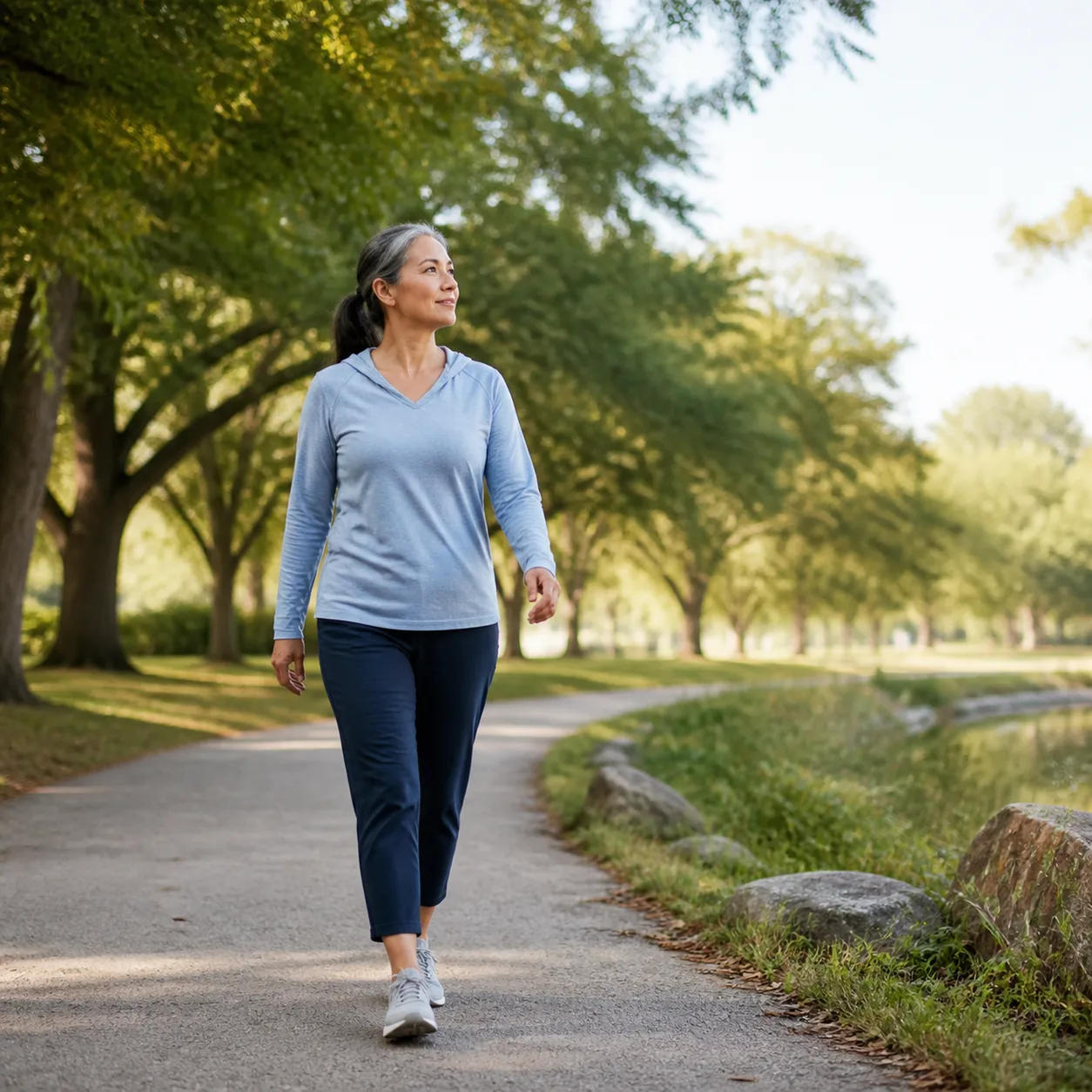 Woman walking along a tree-lined park path as part of an active daily routine